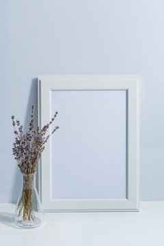 Mock up white frame and lavender on book shelf or desk. White colors. White-blue colors. Minimalistic concept.