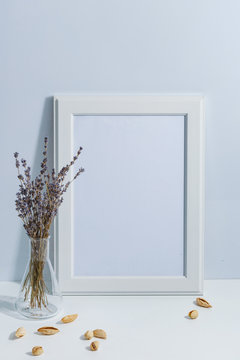 Mock up white frame and lavender on book shelf or desk. White colors. White-blue colors. Minimalistic concept.