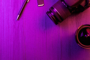 Camera, pencil, fish eye lens and SD card. Pink light. Workspace top view. Copy space. Wood...