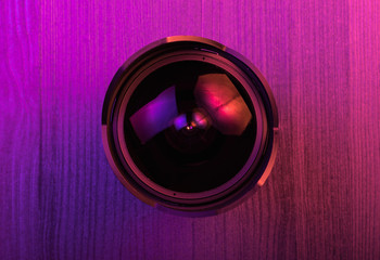 Fish eye lens. Pink light. Workspace top view. Wood background