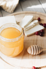 Honey dipper, honey and white flowers on wooden board