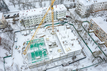 construction site with high yellow tower crane in winter season. aerial top view