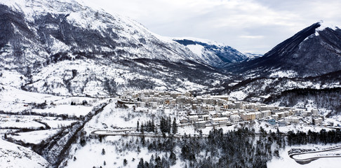 Aerial view of the beautiful snow-covered village of Opi with snow-capped mountains in the...