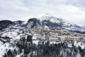 Aerial view of the beautiful snow-covered village of Opi with snow-capped mountains in the background. Opi is a comune and town in the province of L'Aquila in the Abruzzo region of central Italy.