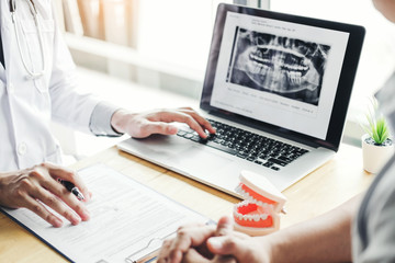 Dentist talking to male patient and presenting results on Dental x-ray film About the problem of the patient in dental office