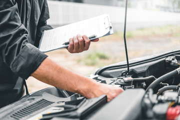 Auto mechanic working in garage Technician holding clipboard and check mechanic Maintenance car check.