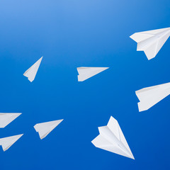 White paper airplanes against the blue sky. The symbol of freedo