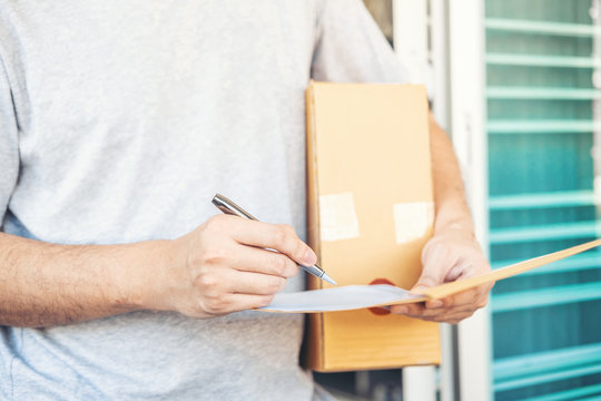 Customer Man signature in clipboard to receive package from professional delivery man at home