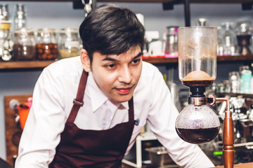 Barista holding and making coffee standing behind the counter bar.Man barista preparing coffee for customer in a cafe