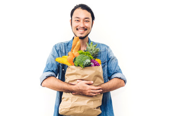 Man holding shopping paper bag with fruit and vegetables on white background