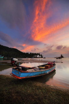 Small fishing boats moored beached on the beach during sunset and the beautiful natural of the colorful sky at Mae Ramphueng Beach Bang Saphan District , Prachuap Khiri Khan province in Thailand.