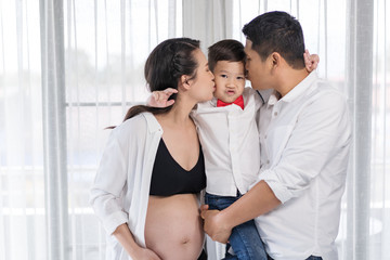happy family concept, pregnant mother and father kissing boy