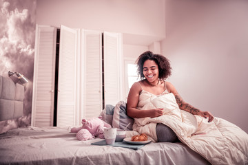 Fototapeta premium Laughing beaming girl sitting wrapped up with blanket
