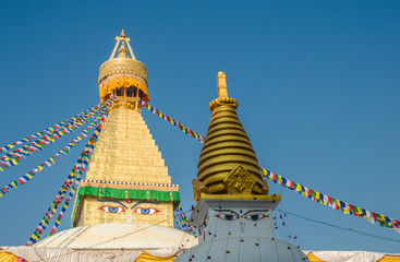 The dome and gold spire of Bodhnath Stupa, Kathmandu, Nepal, with Buddhist prayer flags.