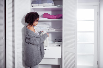 Fototapeta na wymiar African American curly woman choosing clothes in her wardrobe