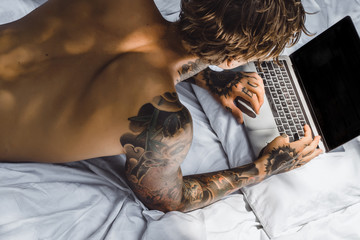 a man in bed working on a laptop, checking mail, watching a movie, listening to music, talking on...