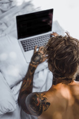 a man in bed working on a laptop, checking mail, watching a movie, listening to music, talking on...