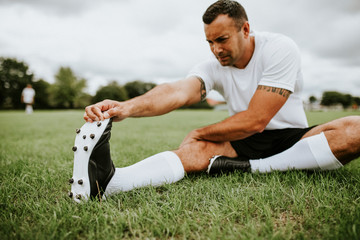 Football player stretching before a match - Powered by Adobe