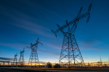 high-voltage power lines and high voltage electric transmission tower in a twilight