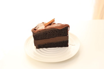 Chocolate cake with cinnamon stick in white table bright background.