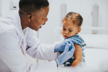 Toddler getting a vaccination by a pediatrician - obrazy, fototapety, plakaty