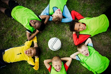 Zelfklevend Fotobehang Junior football team lying around a football © Rawpixel.com