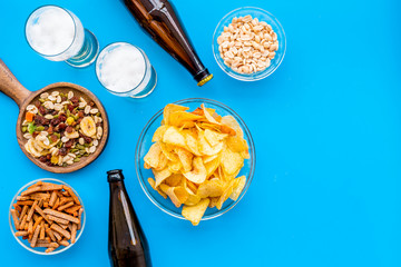 Snacks and beer. Chips, nuts, rusks near beer on blue background top view copy space