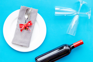 Romantic dinner on Valentine's day. Decorated dishes, tableware, wine on blue background top view