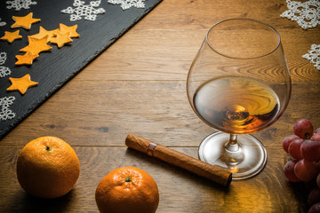 Glass of cognac and cigar with snack on the wood table with stone cutting board. Top view with copy...