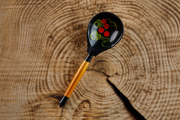 A wooden spoon handmade with a painting in the Russian style of Khokhloma.