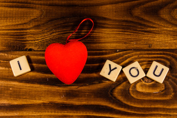 Two red hearts on a wooden table. "I love you" inscription. Top view