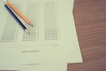 close up top view of pencil over exam answer sheet paper with multiple choice on wood table for world literacy day and education concept	
