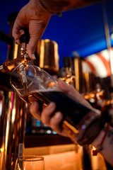 Hand of bartender pouring a large lager beer in tap.