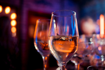Cocktail with ice and lime on a dark wooden bar counter, bokeh bright background