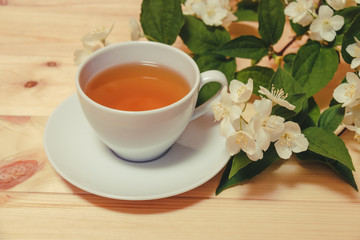 Cup of green tea and jasmine flowers on wooden table. Selective focus.