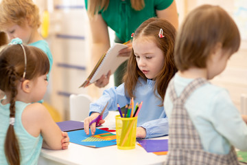 Group of preschool children working with color paper, sciccors and glue on art class in kindergarten