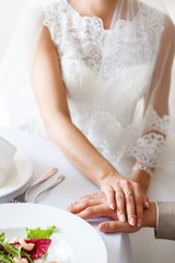 bride and groom hold hands at a table in a restaurant