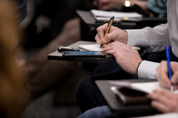 Close-up of businesspeople hands holding pens and papers near table at business seminar