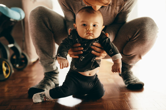 Mother Squatting On Floor With Her Baby