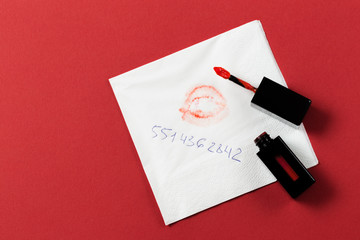 white paper napkin with lipstick and kiss on red background.