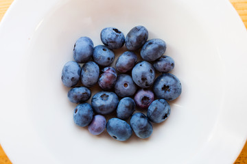Sweet blueberries in the plate on wooden table