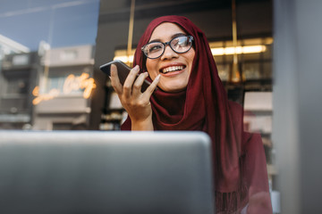 Muslim woman running business online from coffee shop