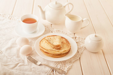 Fototapeta na wymiar Healthy summer breakfast, homemade classic american pancakes with honey,cozy morning, copy space. Pancakes, teapot, honey on white wooden table. Pancake week. russian traditional holiday Maslenitsa