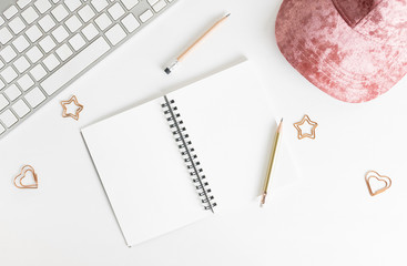 Flat lay top view girly sketchbook mockup: pencils, paper clips, pink hat and keyboard on white background. Clean and bright. Travel concept