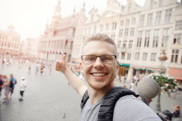 Raamstickers Happy man student with backpack taking selfie photo on central square Brussels, Belgium © Parilov