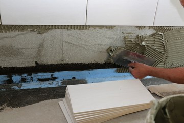 Tiler laying wall tiles in a bathroom