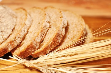 Slices of maroon cereal healthy homemade bread with dried wheat decoration on wooden table background