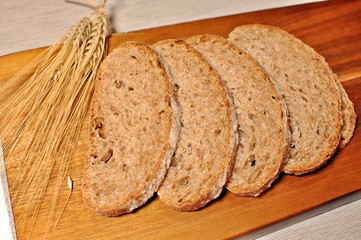 Top table of slices of brown cereal healthy bread with dried wheat decoration on wooden table background