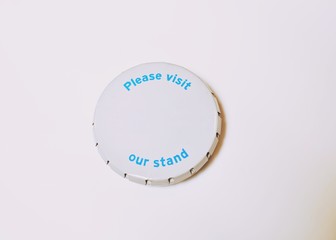 White little round box with inscription Please visit our stand and copy text on white background
