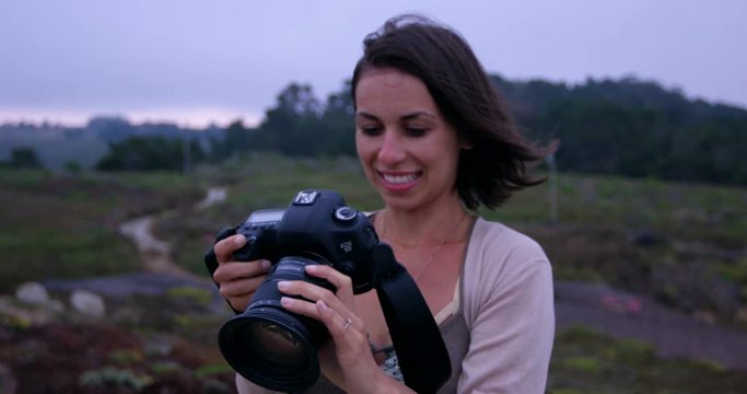 Happy female photographer reviews photo on DSLR and smiles